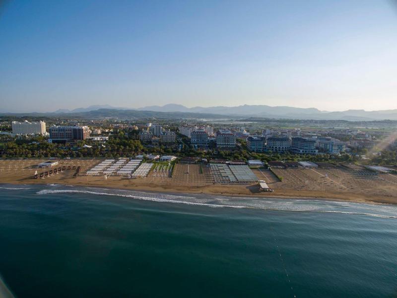 Plaża z piaskiem, budynkami i górami w tle pod czystym niebem.