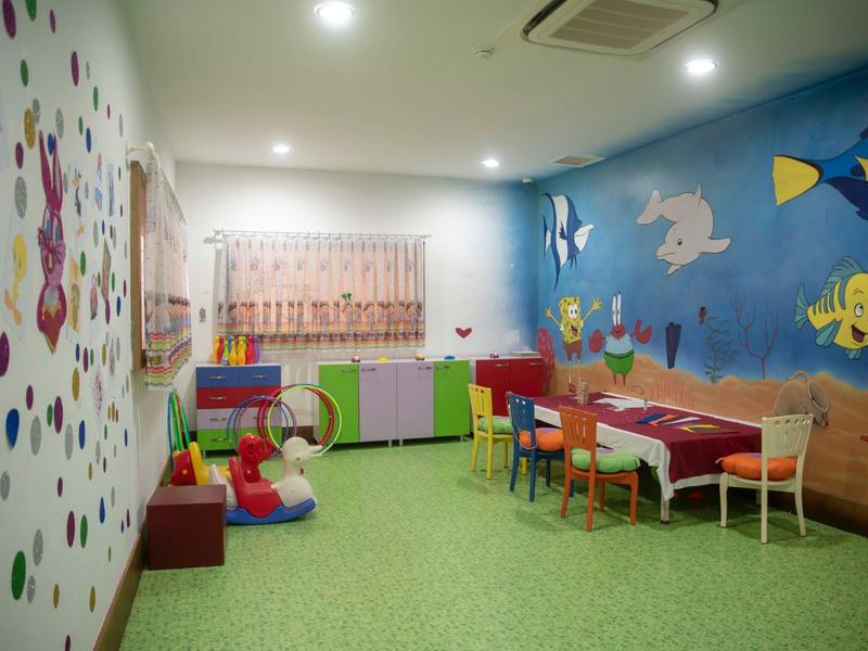 Pokój zabaw dla dzieci z kolorowymi ścianami, stołami, krzesłami i zabawkami w hotelu.