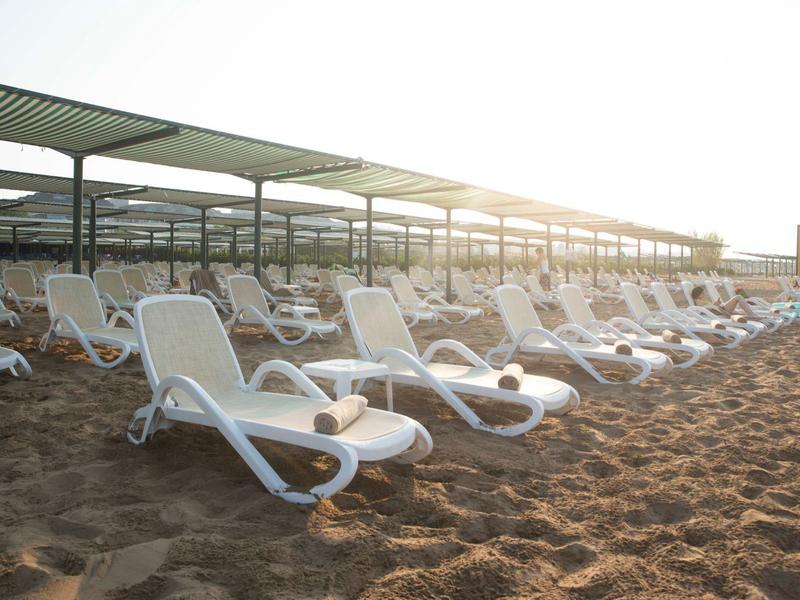 Rząd pustych białych leżaków na piaszczystej plaży o wschodzie słońca