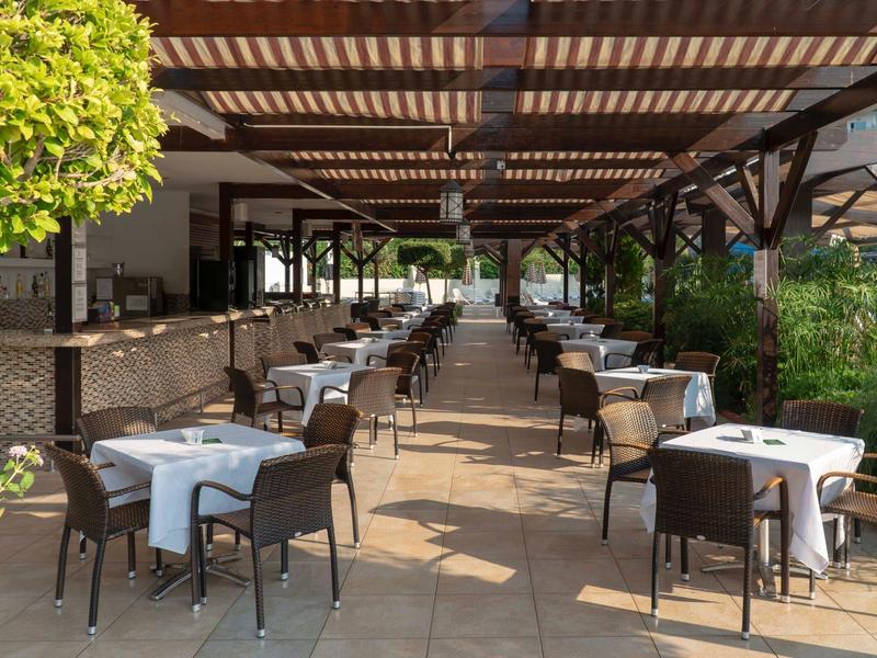 Zadaszony taras na zewnątrz z uporządkowanymi stołami i krzesłami w restauracji.