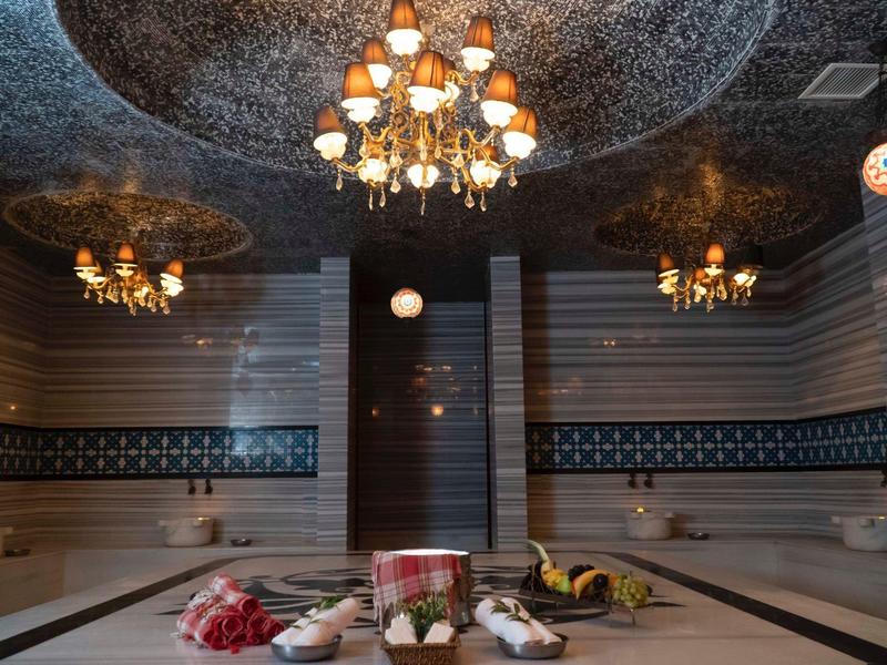 Luksusowy turecki hammam z mozaikowymi wzorami, żyrandolami i zadbanymi akcesoriami spa.