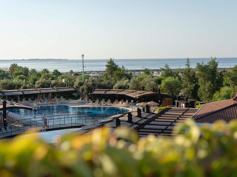 Basen hotelowy z leżakami i widokiem na morze przy czystym niebie.