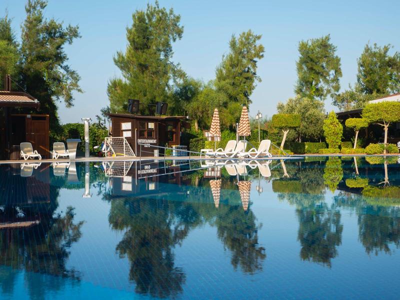 Strefa wypoczynkowa z leżakami i parasolami przy basenie hotelowym w bezchmurną pogodę.