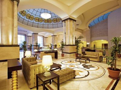 Luxe hotel lobby met elegante zitplaatsen, pilaren en een decoratief koepeldak.