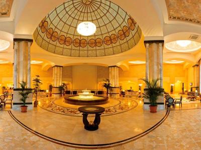 Ruime hotel lobby met bogenramen, sierlijke koepelplafond en stijlvolle zitgedeeltes.