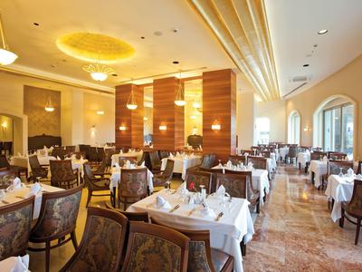 Restaurante elegante con mesas cubiertas de blanco e interior de madera cálida.