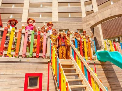 Kinderen staan op een kleurrijke speeltuinbrug in een gebouw met meerdere verdiepingen.