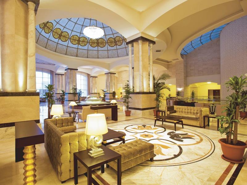 Lichte hotel lobby met elegante zuilen, ronde lampen en comfortabele zitgedeeltes.