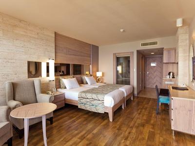 Modern hotel room with two beds, sofa, and wooden floor