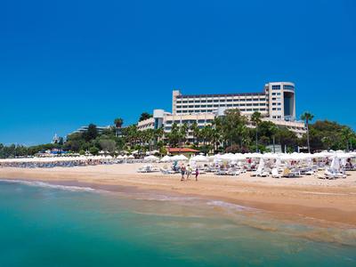 Hotel con vista su una spiaggia di sabbia e ombrelloni sotto un cielo azzurro