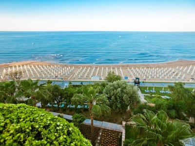 Vista di una spiaggia con ombrelloni e parco verde in primo piano