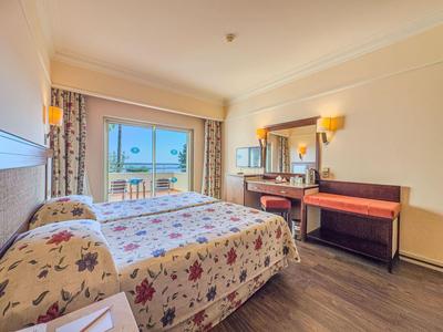 Chambre d'hôtel lumineuse avec lit double et vue sur la mer à travers de grandes fenêtres.