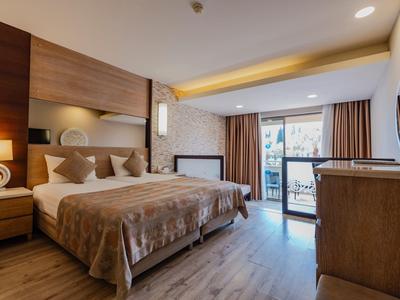 Chambre d'hôtel accueillante avec grand lit, décor en bois et balcon donnant sur l'extérieur.