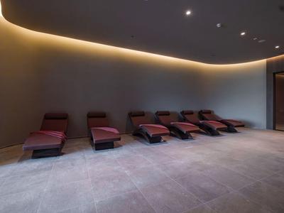 Lounge moderna per il relax con lettini rossi e illuminazione indiretta al soffitto.