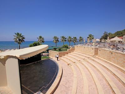 Freiluft-Amphitheater mit Stufen und Blick auf das Meer und Palmen bei klarem Himmel.