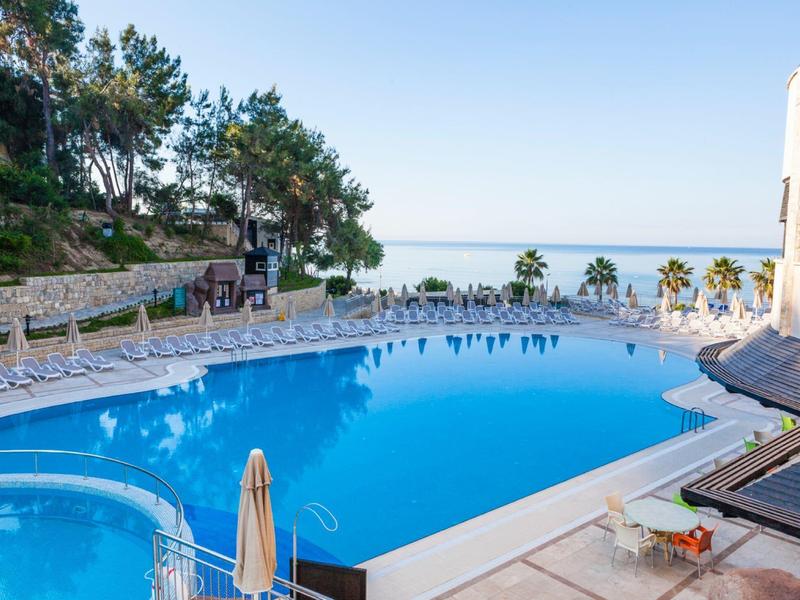 Une grande piscine avec des chaises longues et vue sur la mer par une journée ensoleillée.