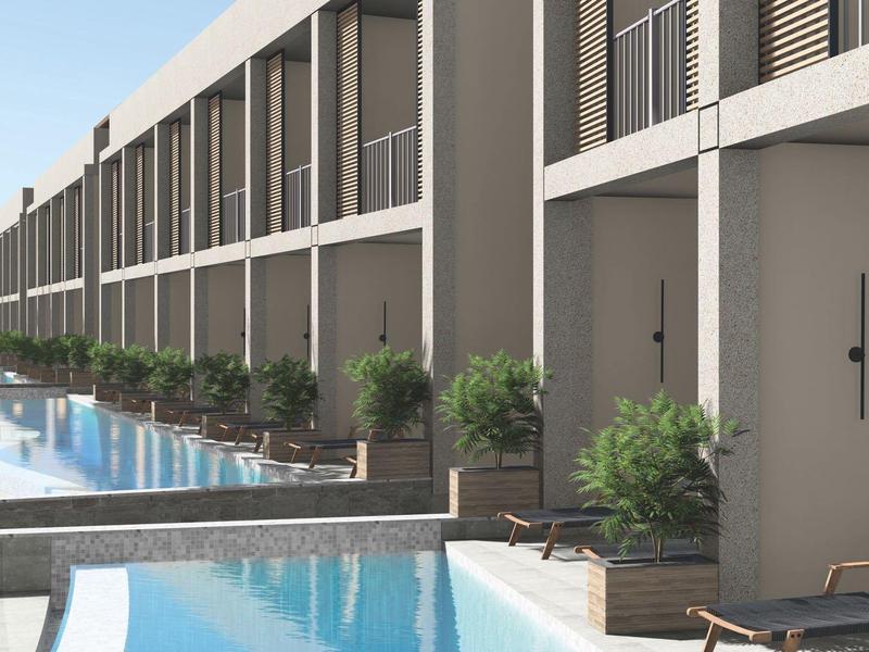 Complexe hôtelier moderne avec piscines privées devant les chambres et vue sur la mer.