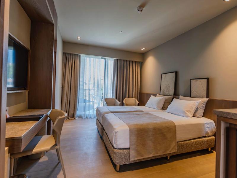 Chambre d'hôtel moderne avec lit double, bureau et accès au balcon.