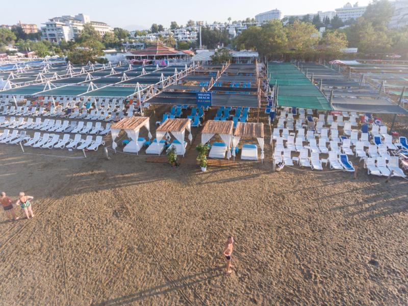 Playa con filas de tumbonas y sombrillas en un resort vacacional junto al agua.