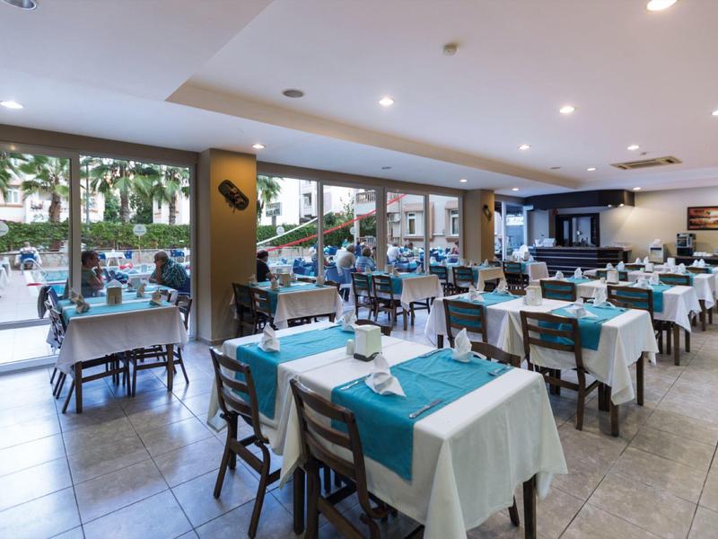 Restaurante luminoso con manteles blancos, caminos de mesa azules y gran ventanal hacia el exterior.