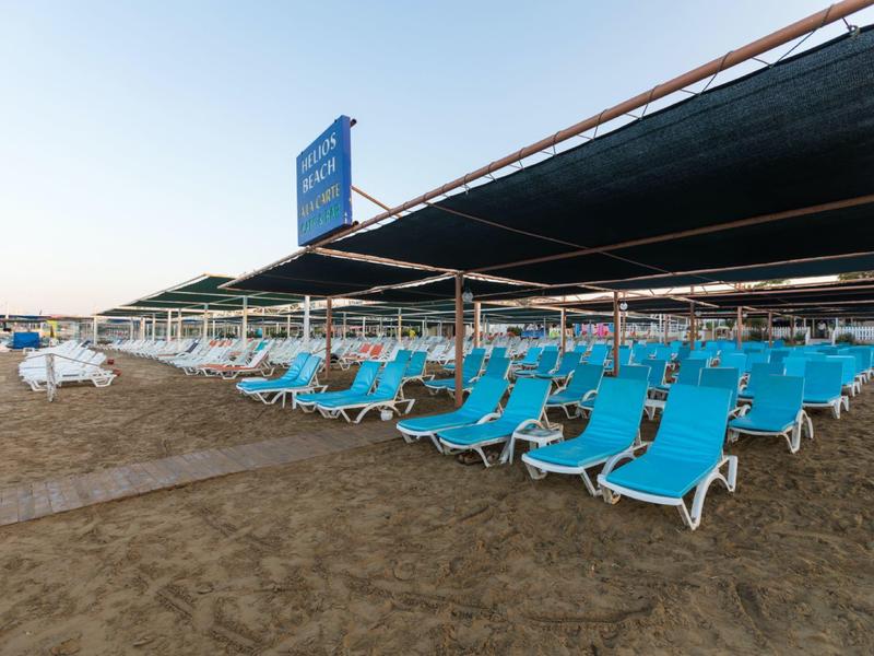 Fila de hamacas azules en la playa bajo sombra con cielo despejado.