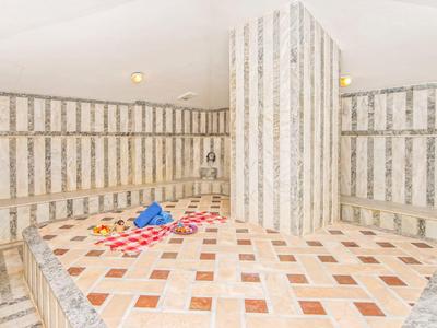 Przestronny hammam z marmurowymi ścianami i kolorowymi wzorami na centralnej platformie.