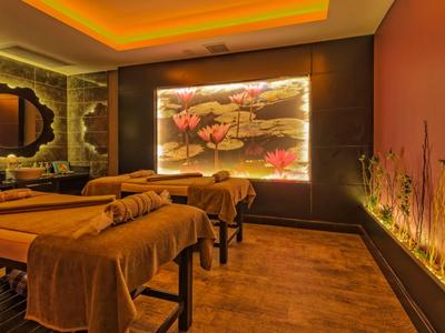 Przytulny pokój do masażu z miękkim oświetleniem i kwiatową dekoracją.