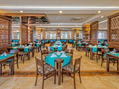 Przestronna jadalnia z drewnianymi stołami i turkusowymi serwetkami.