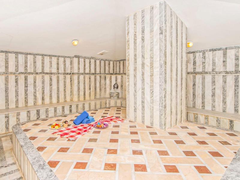 Przestronny hammam z marmurowymi ścianami i kolorowymi wzorami na centralnej platformie.