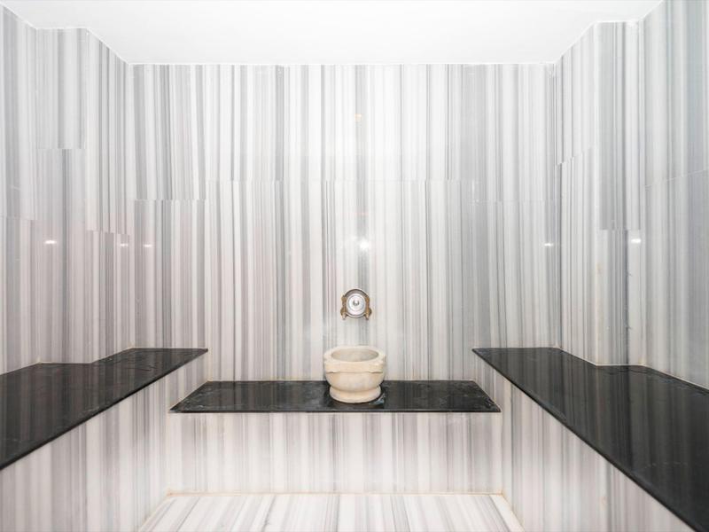 Wnętrze hammamu z gładkimi, czarno-białymi marmurowymi ścianami i ławkami.