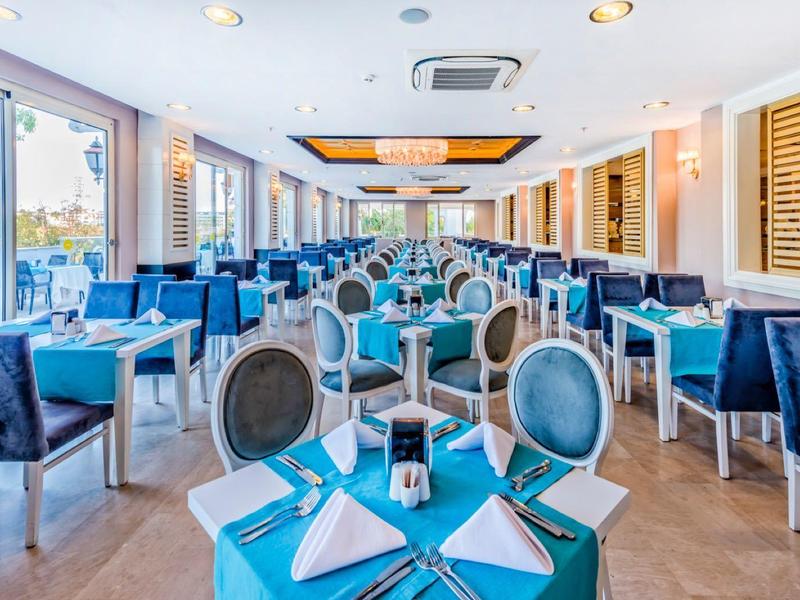 Nowoczesna jadalnia z dużymi oknami i elegancko nakrytymi stolikami.