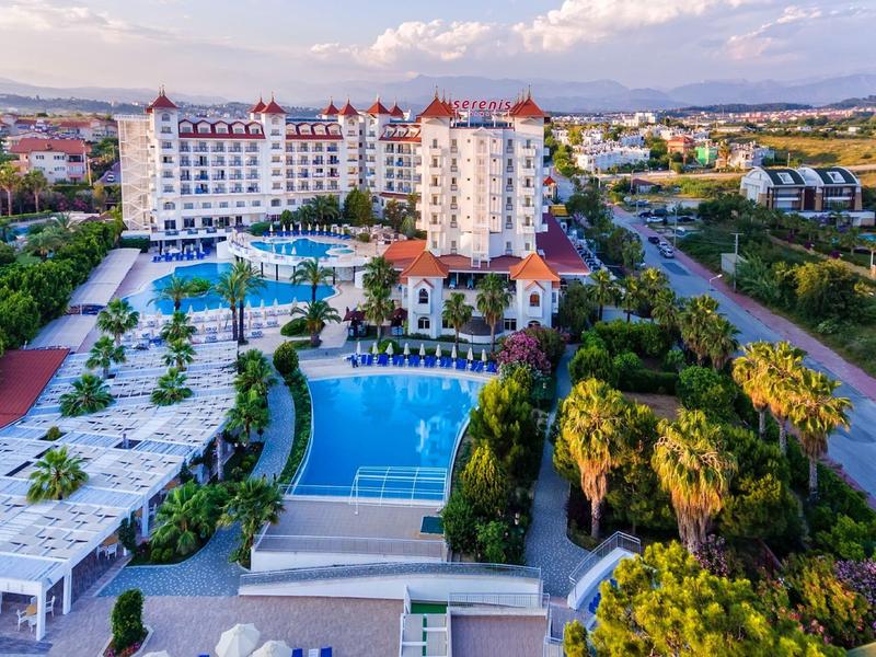 Duży kompleks hotelowy z basenami i bujnymi ogrodami pod częściowo zachmurzonym niebem.