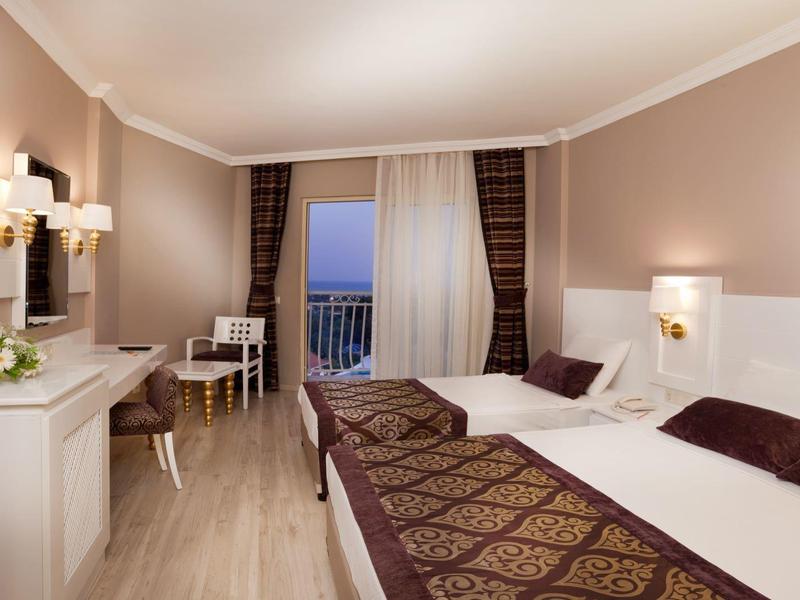 Nowoczesny pokój hotelowy z widokiem na morze, podwójnym łóżkiem i biurkiem.