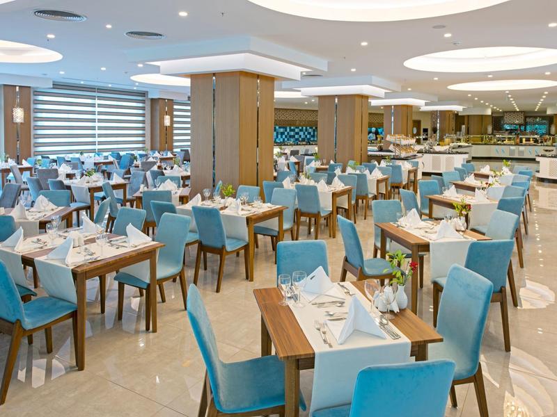 Restaurante elegante de hotel con sillas azules y mesas preparadas en un espacio moderno y luminoso.