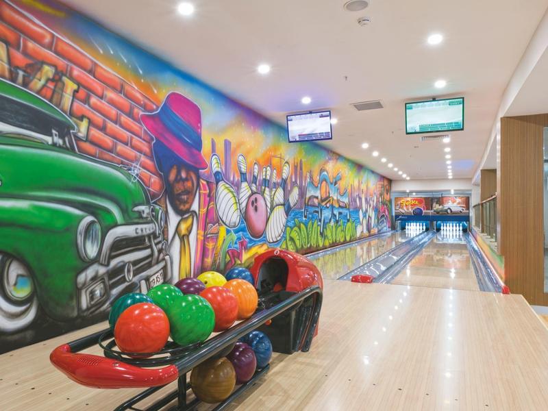 Pista de bolos moderna con grafiti colorido en la pared y bolas de bolos de colores en el hotel
