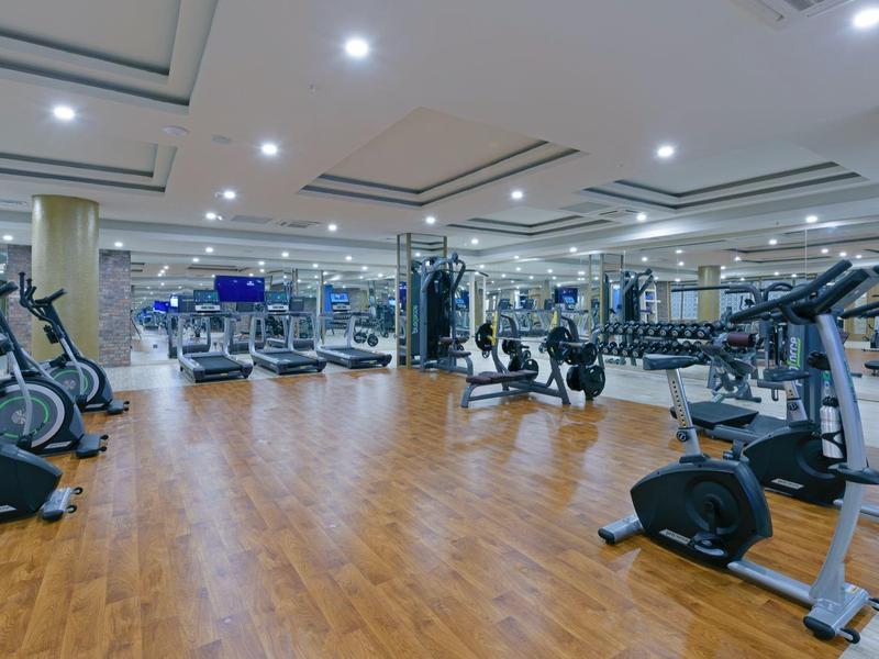 Amplio gimnasio moderno con suelo de madera y varios equipos de entrenamiento en un hotel.