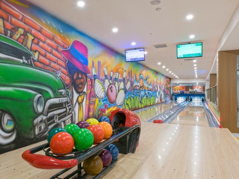 Pista de bolos moderna con bolas de bolos coloridas y grafiti colorido en la pared de un vestíbulo de hotel.