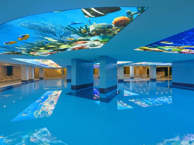 Gran piscina interior con agua azul y techo con motivo submarino en hotel