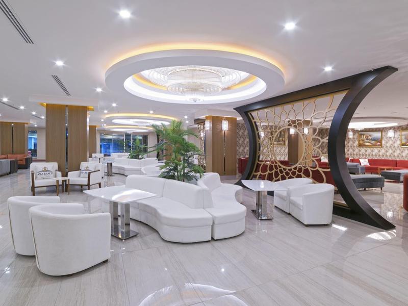 Área de lounge de hotel moderno y elegante con sofás blancos e iluminación estilizada.