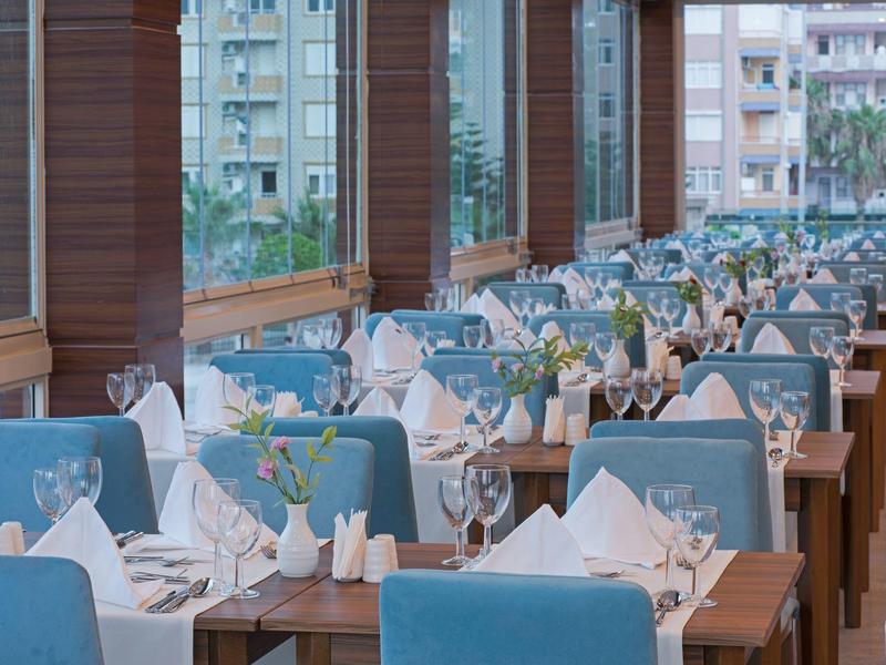Restaurante elegante con sillas azules y mesas preparadas en un hotel con vista a la ciudad.