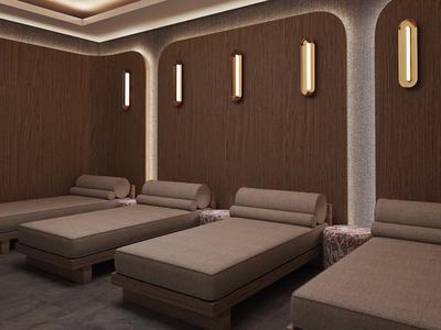 Moderne ontspanningsruimte met vier beklede ligstoelen en warme wandlampen in een rustige sfeer.