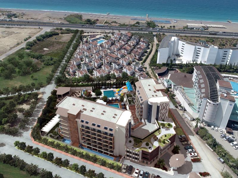 Luchtfoto van een hotel en resort aan zee met zwembad, parkeergelegenheid en strand op de achtergrond.