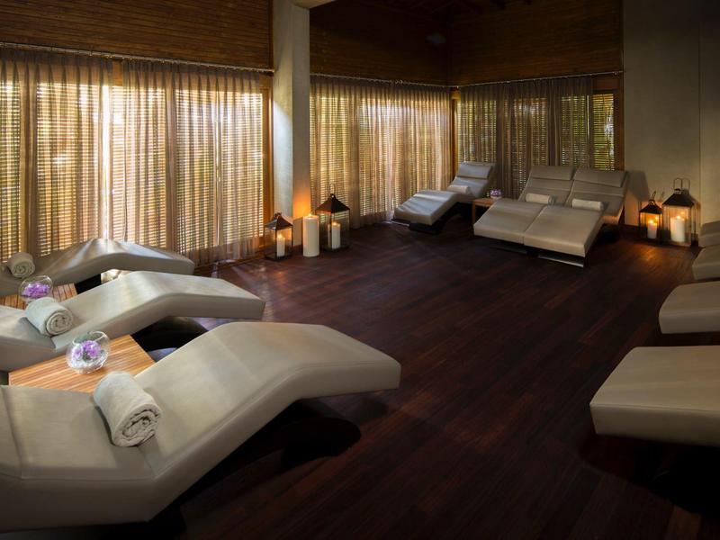 Acogedora sala de descanso de spa con tumbonas, luz tenue y toallas listas.