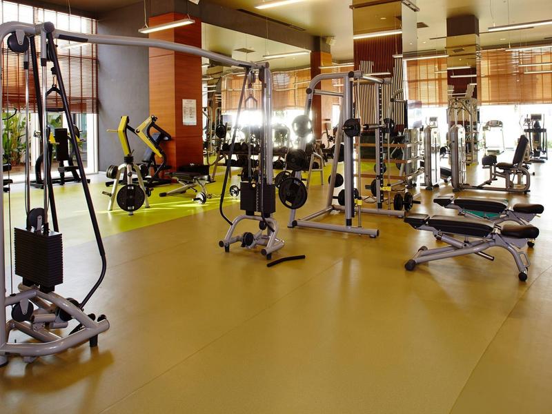 Gimnasio espacioso con equipos modernos, bancos y pesas para uso de huéspedes del hotel.
