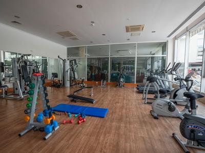 Palestra luminosa con pavimento in legno, parete a specchio, attrezzi per allenamento e grandi finestre.