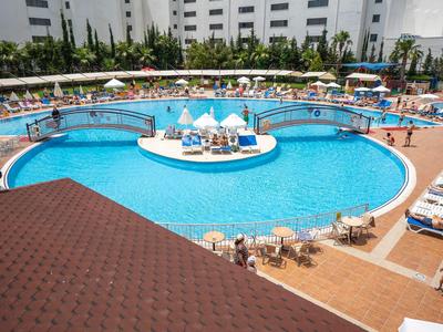 Grande piscina dell'hotel con isola centrale, ponti e lettini, circondata da edifici.