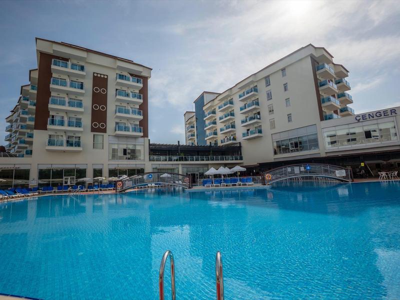 Velký hotel s několika patry a velkým venkovním bazénem za slunečného počasí.