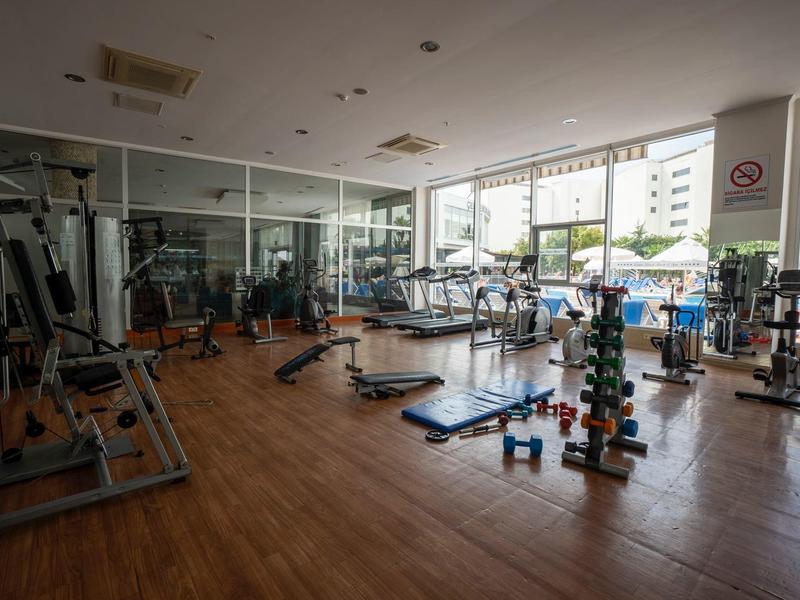 Interiér světlé posilovny s cvičebními přístroji a činkami.