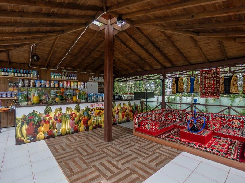 Tradiční posezení s polštáři a barevnou výzdobou v zastřešeném stánku na cestovatelském trhu.