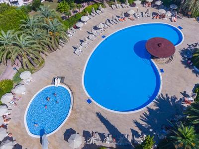 Luchtfoto van twee zwembaden met ligstoelen en parasols in een tropisch hotelresort.